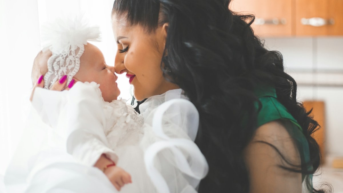 Mother holding her young baby girl close to a kiss.
